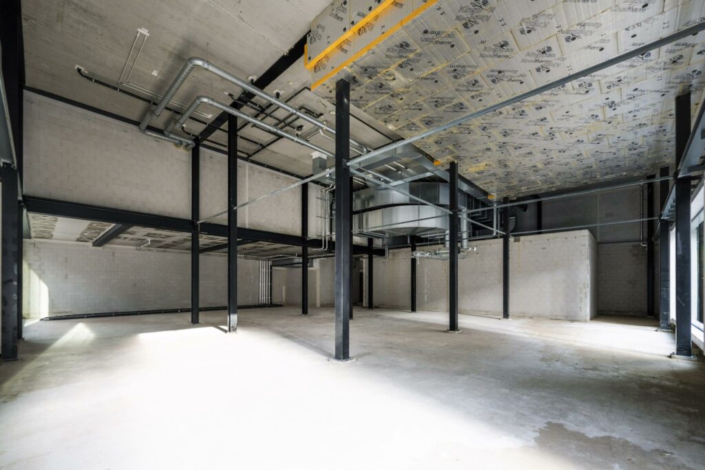 Lege industriële bedrijfsruimte aan de Pieter Goosstraat met zicht op betonnen muren, stalen constructie en ventilatiekanalen.